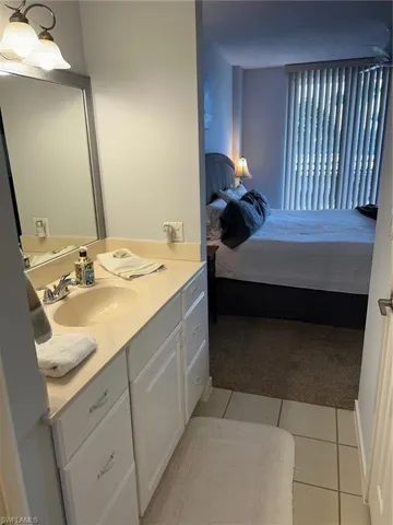 Bathroom with ensuite bathroom, vanity, light carpet, and light tile patterned flooring