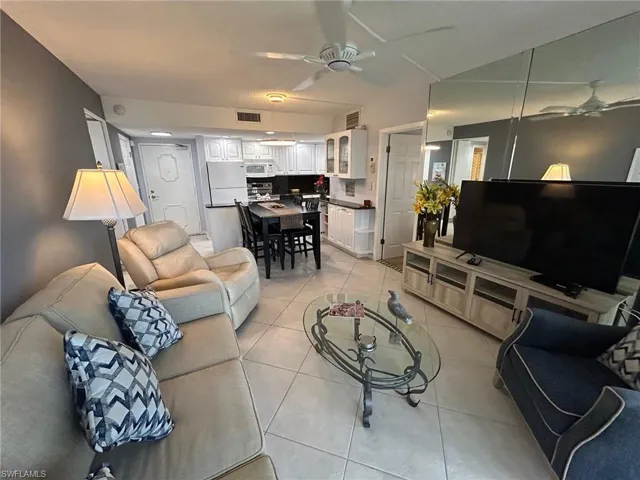 Living room with ceiling fan and light tile patterned flooring