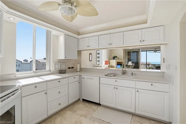 Kitchen with a ceiling fan, white cabinetry, white appliances, and crown molding - Virtually Edited Image