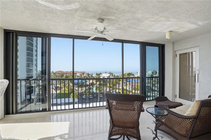 Sunroom with floor to ceiling windows, a textured ceiling, and tile patterned floors - Virtually Edited Image