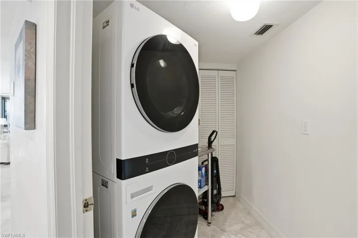 Laundry room featuring stacked washing machine and dryer and baseboards - Virtually Edited Image