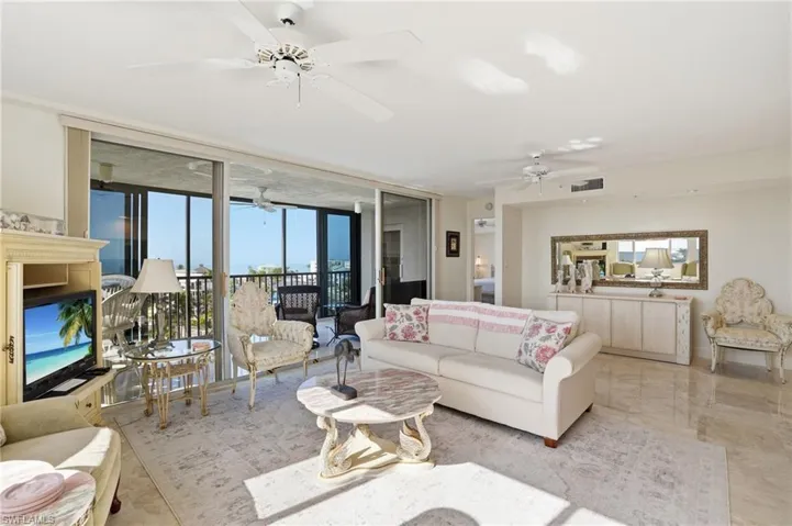 Living area featuring floor to ceiling windows, marble tiled floors, and ceiling fan - Virtually Edited Image