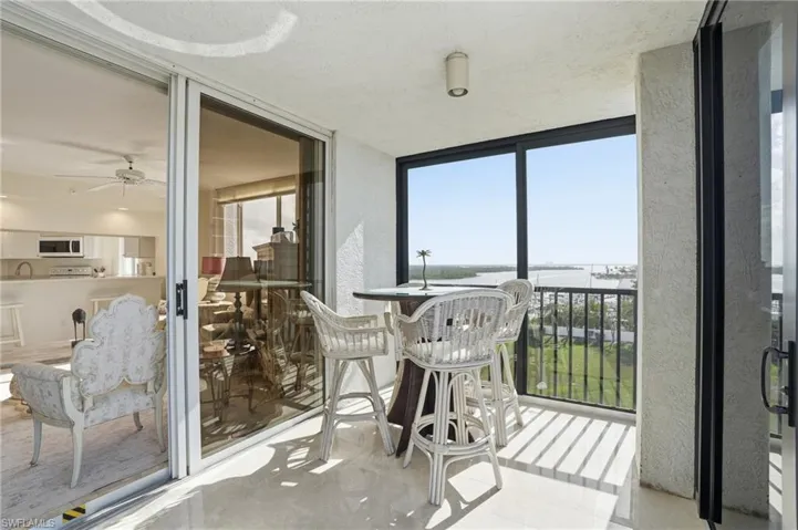 Sunroom featuring expansive windows and a water view - Virtually Edited Image