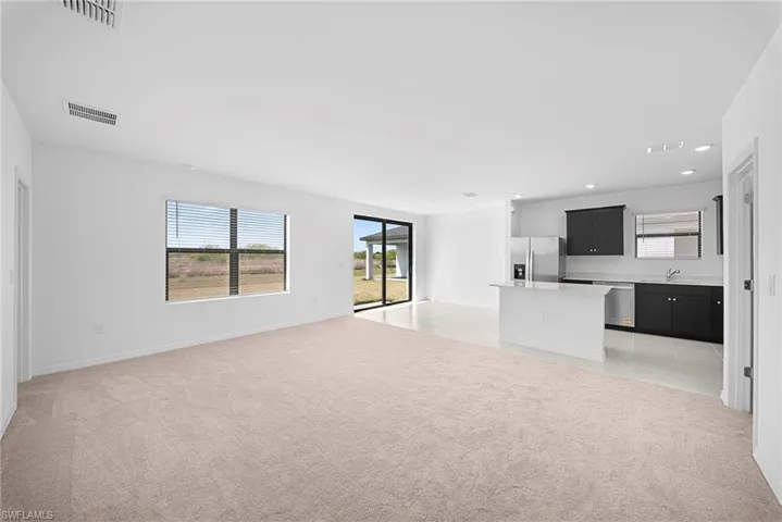 Unfurnished living room featuring light carpet, plenty of natural light, and recessed lighting
