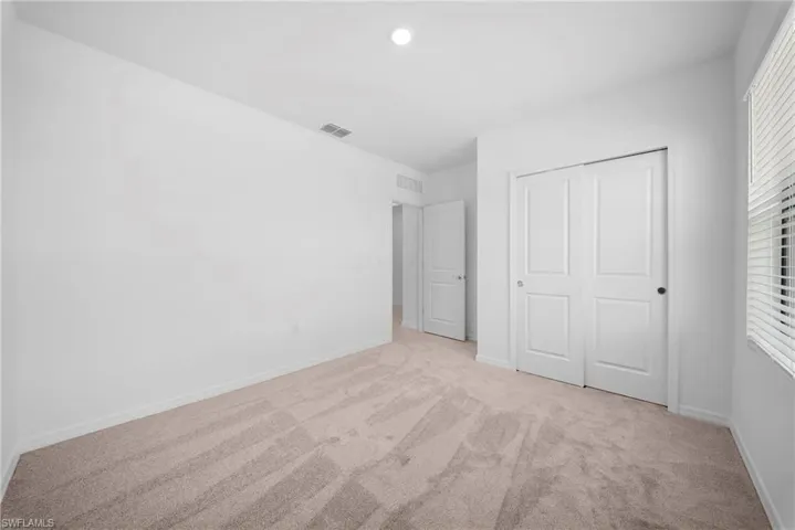 Unfurnished bedroom with light colored carpet and a closet