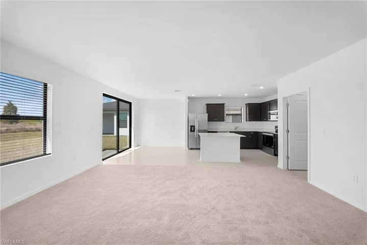 Unfurnished living room featuring light carpet, recessed lighting, and light tile patterned floors