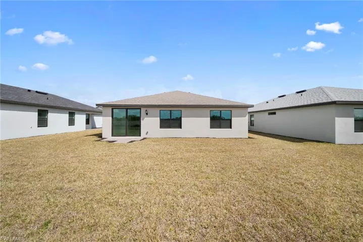Back of property featuring a yard, stucco siding, and a patio area