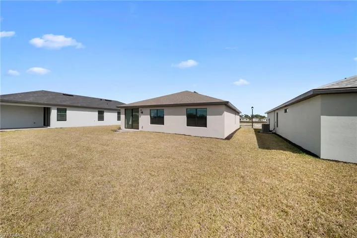 Rear view of property with a yard and stucco siding