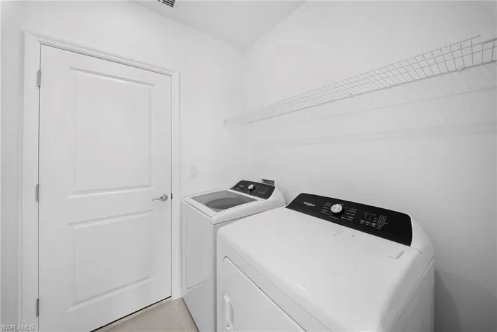 Laundry area featuring washing machine and clothes dryer and light tile patterned flooring