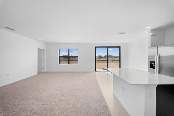 Unfurnished living room featuring light carpet and light tile patterned flooring