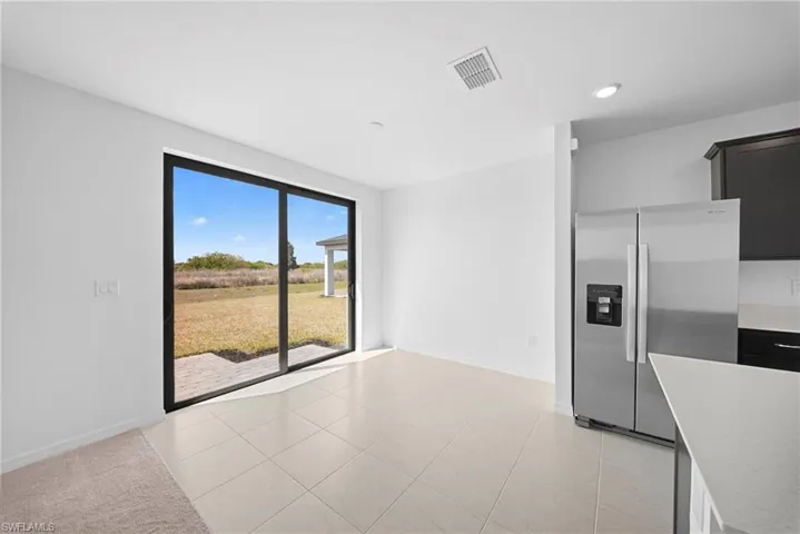 Kitchen featuring stainless steel refrigerator with ice dispenser and light tile patterned floors