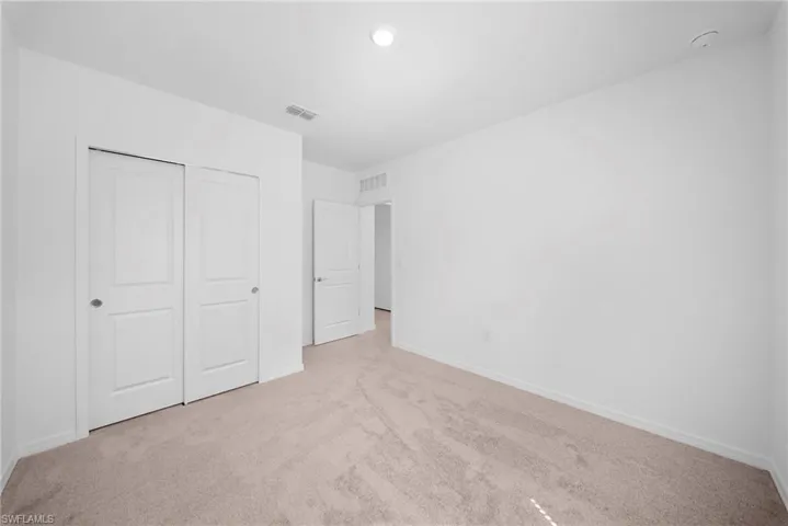 Unfurnished bedroom featuring light carpet and a closet
