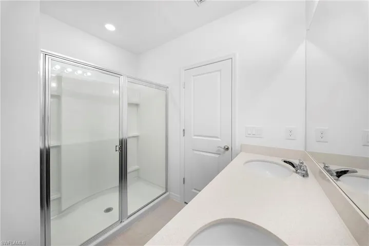 Full bathroom featuring a stall shower, double vanity, and light tile patterned flooring
