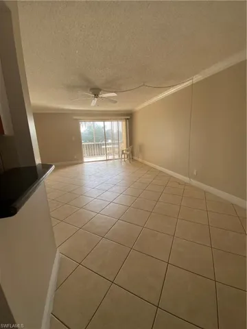 Tiled spare room featuring crown molding, a textured ceiling, and ceiling fan