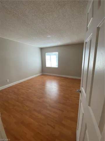Empty room with a textured ceiling and hardwood / wood-style flooring