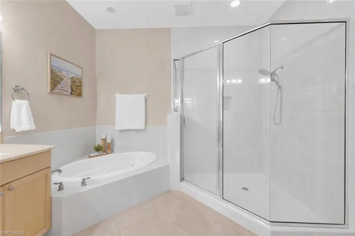 Bathroom featuring a bath, a stall shower, vanity, and light tile patterned floors