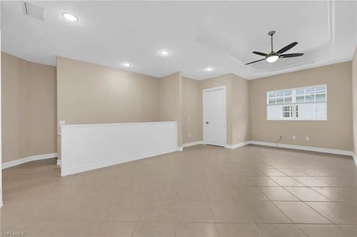 Empty room with a ceiling fan, recessed lighting, a raised ceiling, and light tile patterned flooring