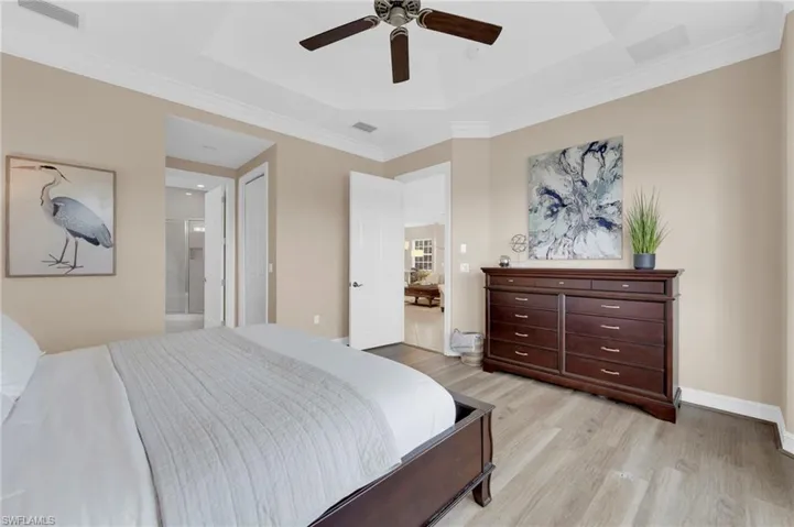 Bedroom featuring ornamental molding, ensuite bath, light wood finished floors, and a ceiling fan