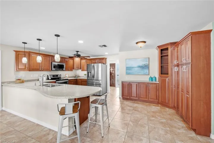 Open kitchen breakfast bar seating, solid surface counters, custom cabinetry