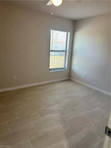 Empty room featuring baseboards and ceiling fan