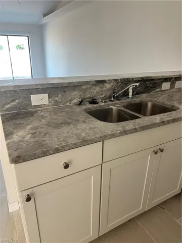 Kitchen with white cabinets, dark stone countertops, and light wood-style flooring