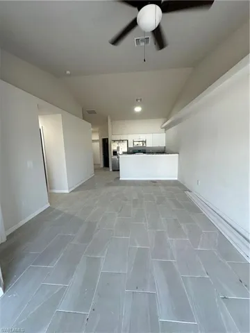 Unfurnished living room featuring lofted ceiling and ceiling fan