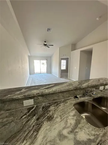 Unfurnished living room featuring ceiling fan and vaulted ceiling