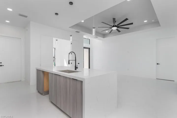 Kitchen with modern cabinets, recessed lighting, a raised ceiling, light marble finish floors, and ceiling fan