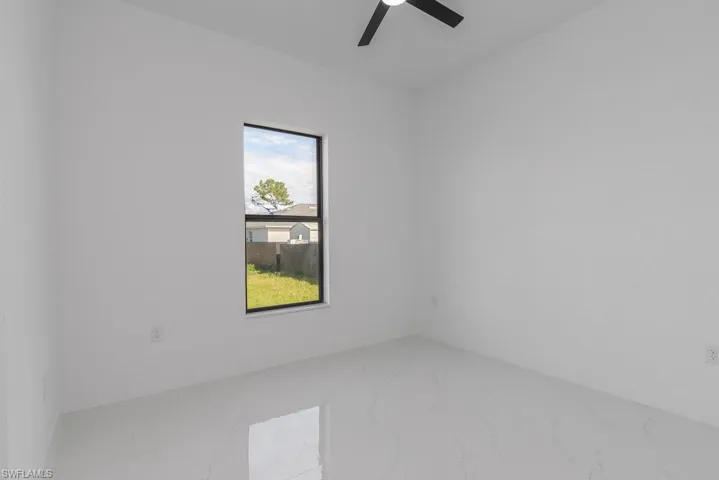 Spare room with marble finish floors and a ceiling fan