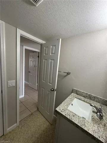 Bathroom with vanity, a textured ceiling, and baseboards