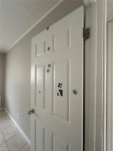 Detailed view of a textured ceiling, baseboards, and a textured wall