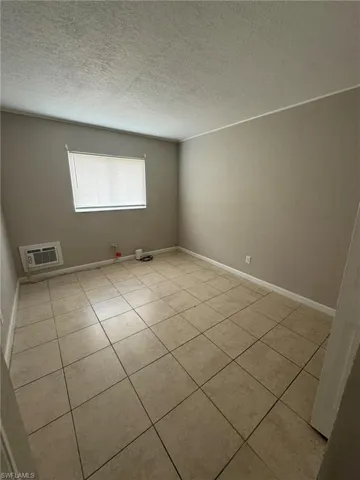 Empty room featuring tile patterned floors, a textured ceiling, and baseboards