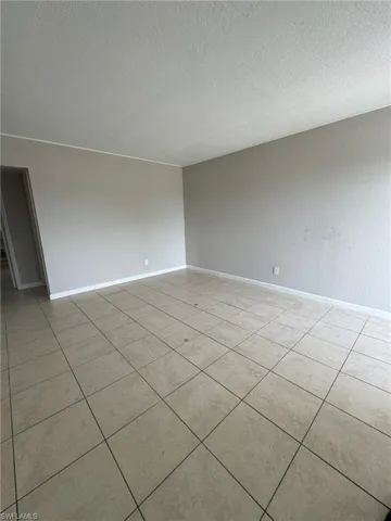 Unfurnished room featuring a textured ceiling, baseboards, and light tile patterned flooring