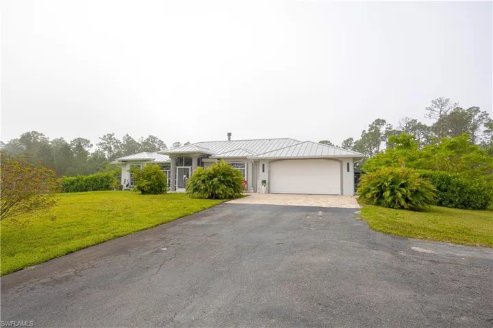 Ranch-style home with metal roof, a garage, a standing seam roof, and aphalt driveway