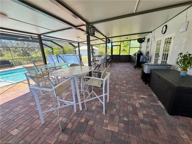View of patio / terrace featuring french doors, an outdoor pool, outdoor dining area, and glass enclosure