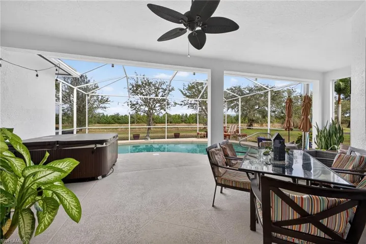 Outdoor pool with a patio, a sunroom, glass enclosure, outdoor dining area, and a hot tub