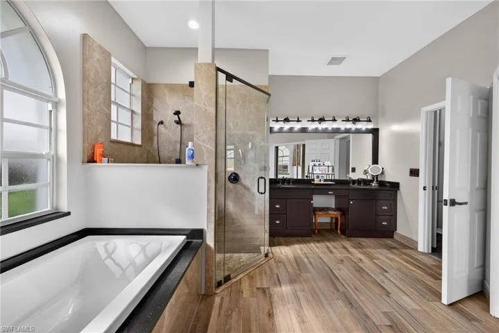 Full bathroom with vanity, a bath, light wood-style flooring, and a stall shower