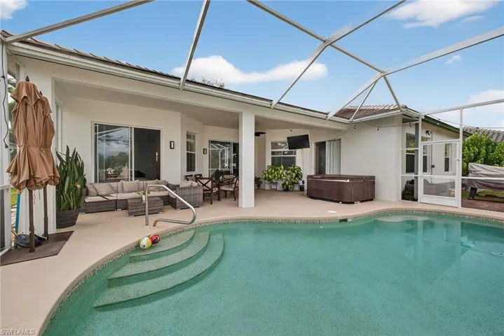 Swimming pool with a sunroom, a hot tub, glass enclosure, and a patio
