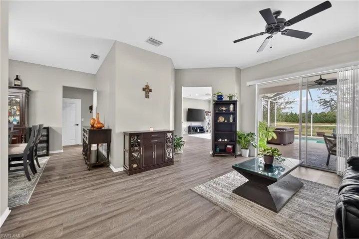 Living room featuring wood finished floors, a ceiling fan, and a sunroom