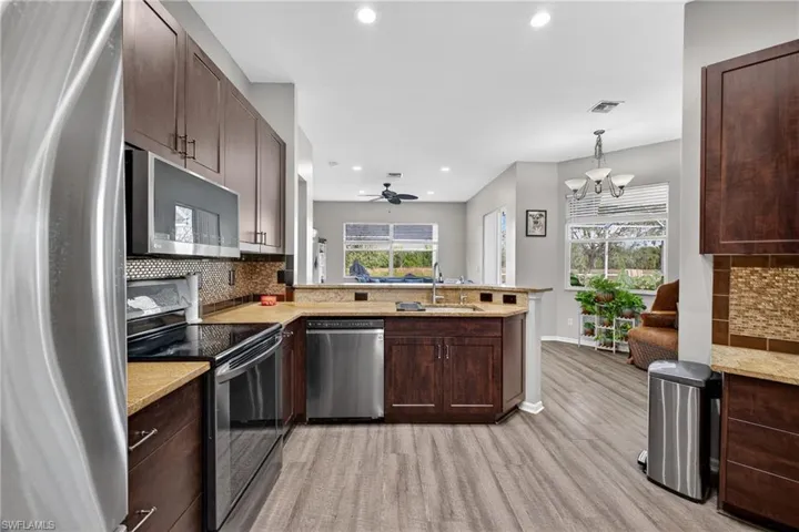Kitchen featuring appliances with stainless steel finishes, backsplash, dark brown cabinets, recessed lighting, and a peninsula