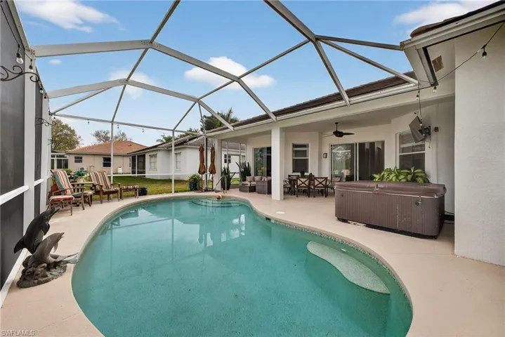 Outdoor pool featuring a sunroom, an outdoor living space, a patio, and a hot tub