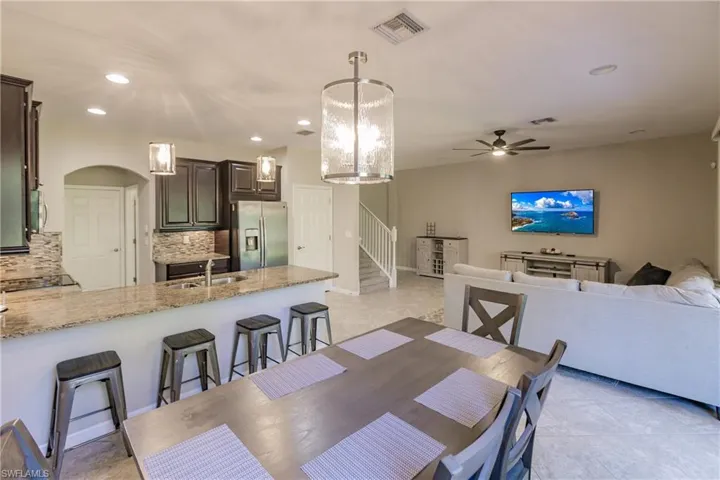 Dining space featuring light tile patterned floors, sink, and ceiling fan with notable chandelier