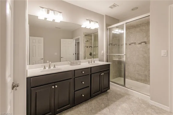 Bathroom with tile patterned floors, an enclosed shower, and vanity