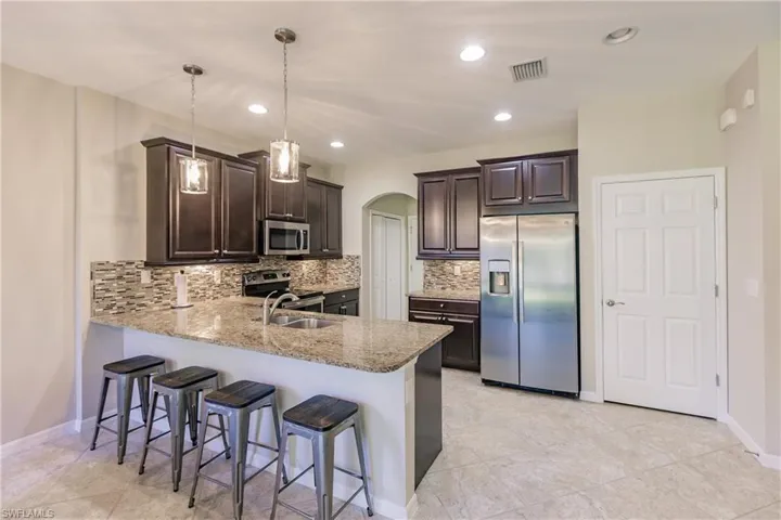 Kitchen featuring decorative light fixtures, stainless steel appliances, decorative backsplash, sink, and kitchen peninsula
