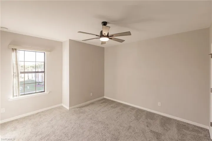 Carpeted empty room featuring ceiling fan