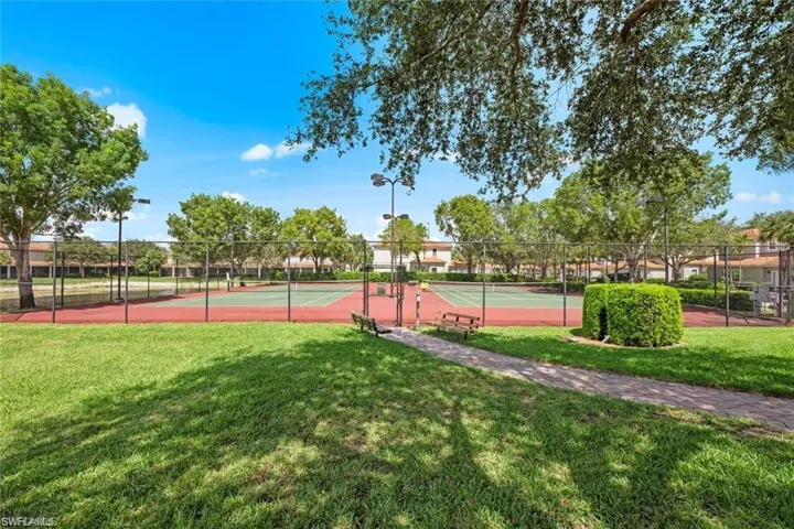 View of tennis court featuring a yard
