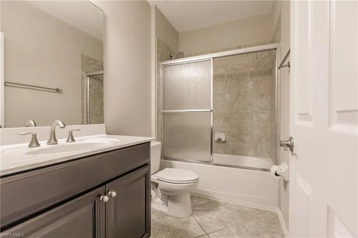 Full bathroom with toilet, enclosed tub / shower combo, tile patterned flooring, and vanity