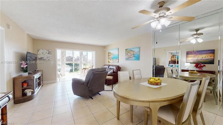 Open-concept living and dining area featuring tile flooring, a built-in wall mirror, and large sliding glass doors providing access to the exterior