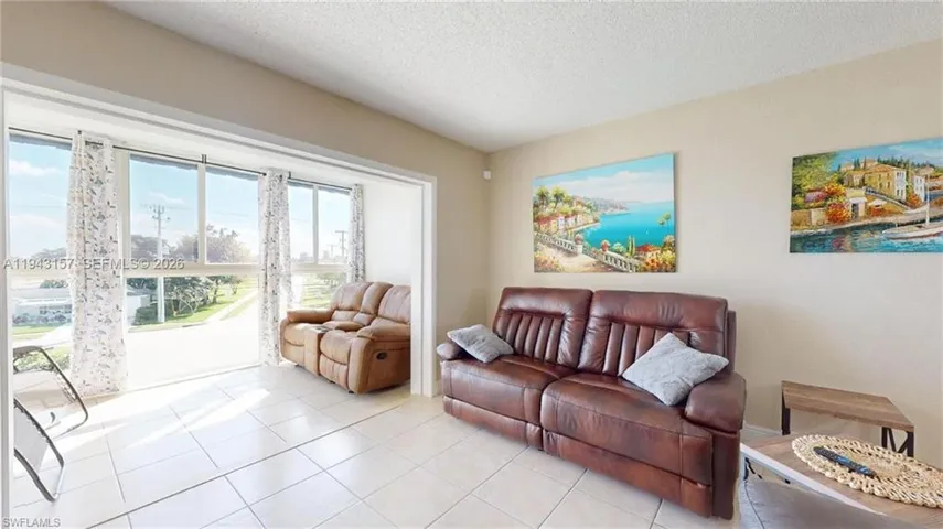 Bright living space featuring large windows, neutral wall tones, and tiled flooring