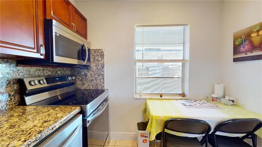 Kitchen featuring rich wood cabinetry, stainless steel appliances, speckled stone countertops, and a coordinating stone backsplash